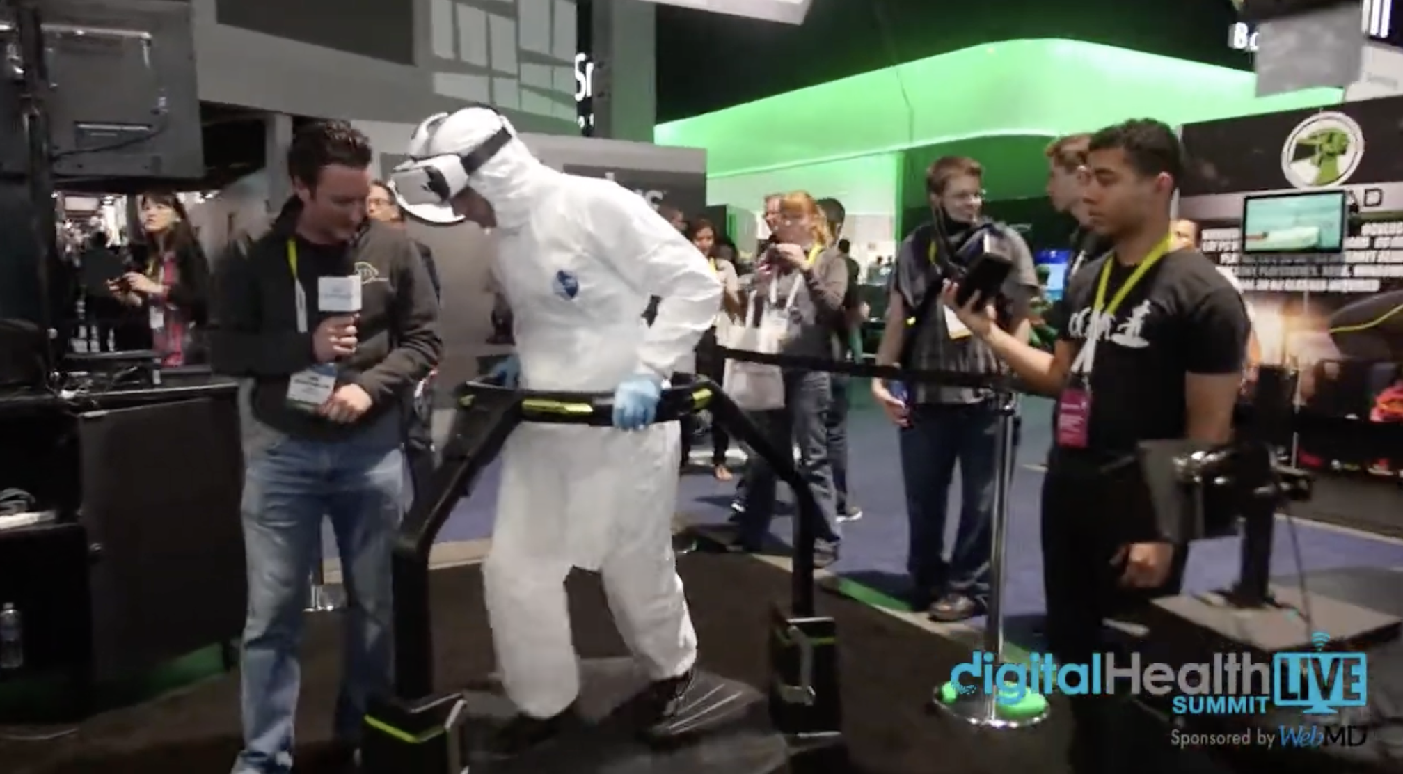 A participant in protective medical gear uses a VR treadmill during an Ebola training demonstration